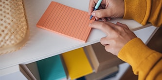 A person making notes on an orange lined Post-it&reg; Note
