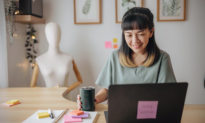 Woman sitting at a desk in a cosy and organised space, surrounded by décor
