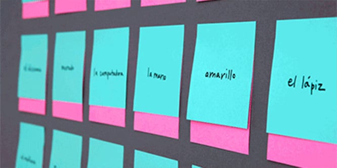 A wall covered with Post-it® Notes featuring Spanish words, used for practicing language
