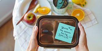 A lunchbox with heartfelt message on a Post-it&reg; Note saying "You're the reason for my smile"
