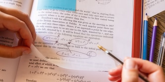 A student annotating a textbook with a Post-it&reg; Transparent Note, highlighting mathematical equations

