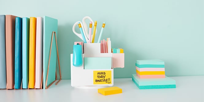 A desk with colourful notebooks, pencils, scissors, and Post-it® Notes, creating an organised and cosy workspace
